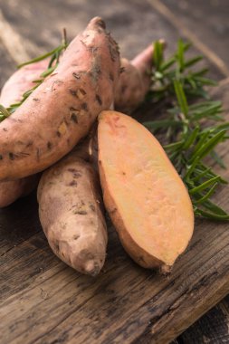 Tahta arka planda tatlı patates, yakın plan. Çiğ patates ya da otlu yarasa.