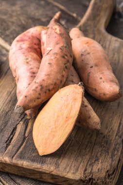Tahta arka planda tatlı patates, yakın plan. Çiğ patates ya da otlu yarasa.