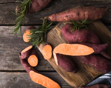 Tahta arka planda tatlı patates, yakın plan. Çiğ patates ya da otlu yarasa.