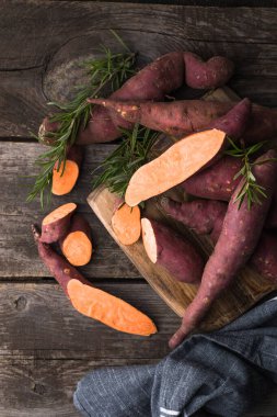 Tahta arka planda tatlı patates, yakın plan. Çiğ patates ya da otlu yarasa.