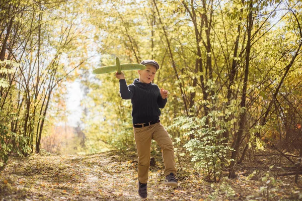 若い男の子が手におもちゃの飛行機で遊ぶ ハッピーキッドは屋外の公園で遊んでいます — ストック写真