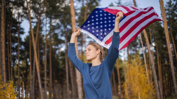 アメリカ国旗の美しい少女 暖かい夏の森で手にアメリカ国旗 — ストック写真