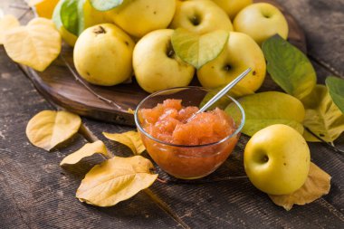 Ahşap bir arka planda cam kavanozda taze ev yapımı elma reçeli. Birkaç taze elma.