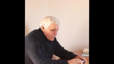 Kanepede otururken akıllı telefon kullanan gülümseyen yaşlı adam.. 
