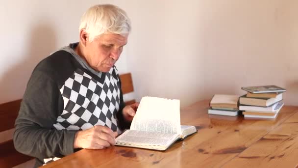 Senior priant, lisant une vieille Bible dans ses mains. — Video