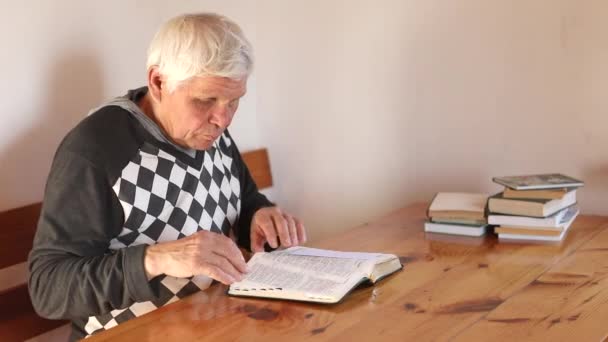 Senior man bidt, leest een oude bijbel in zijn handen. — Stockvideo