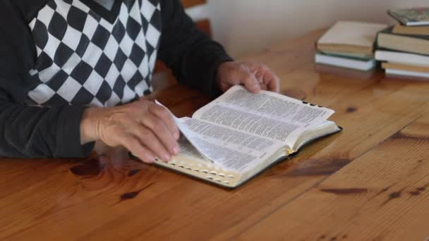 Senior man bidt, leest een oude bijbel in zijn handen. — Stockvideo