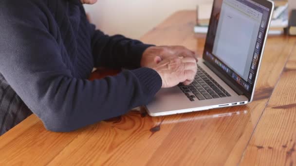 Gubben jobbar på laptop hemma. Senior man använder dator i vardagsrummet — Stockvideo