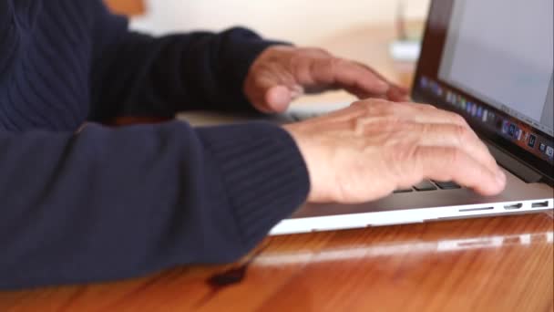 Een oude man die thuis aan een laptop werkt. Senior man met computer in de woonkamer — Stockvideo