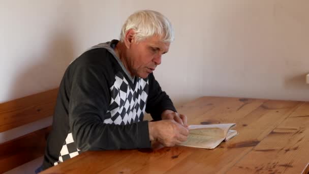 Senior man leest een boek. Ontspanning, vrije tijd, onderwijs. — Stockvideo