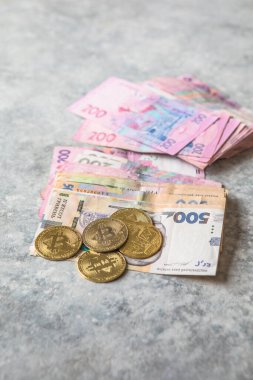 Ukrayna hrivniası banknotları ve altın bitcoinler. Kripto para birimi yatırım kavramı.