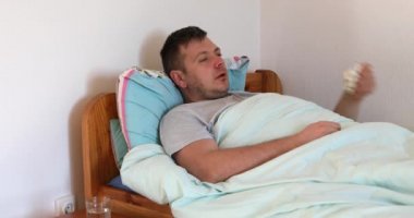 Hasta adam yatakta yatıyor ve kendini kötü hissediyor. Erkek evde dinleniyor, nezle belirtilerini hissederken kadın da alına dokunarak ateşi kontrol ediyor..