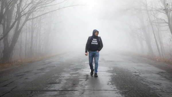 孤独な男の霧の距離の道路を歩く 朝の霧の中で道路と農村風景 暖かい秋の色 暗い神秘的な背景 — ストック写真