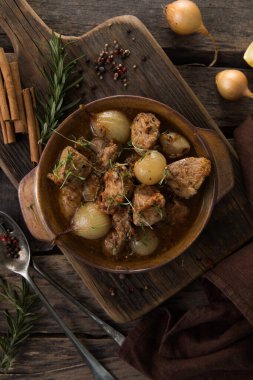 stifado - lezzetli Akdeniz sığır güveci soğan soğanları, tarçın ve baharatlar bir güveçte, siyah ahşap bir masa üzerinde, yukarıdan görüş, yakın çekim