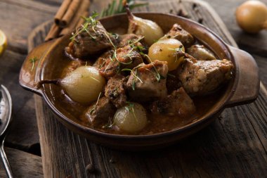 stifado - lezzetli Akdeniz sığır güveci soğan soğanları, tarçın ve baharatlar bir güveçte, siyah ahşap bir masa üzerinde, yukarıdan görüş, yakın çekim
