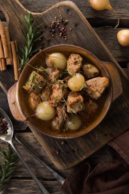 stifado - lezzetli Akdeniz sığır güveci soğan soğanları, tarçın ve baharatlar bir güveçte, siyah ahşap bir masa üzerinde, yukarıdan görüş, yakın çekim