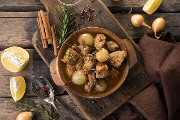 stifado - lezzetli Akdeniz sığır güveci soğan soğanları, tarçın ve baharatlar bir güveçte, siyah ahşap bir masa üzerinde, yukarıdan görüş, yakın çekim