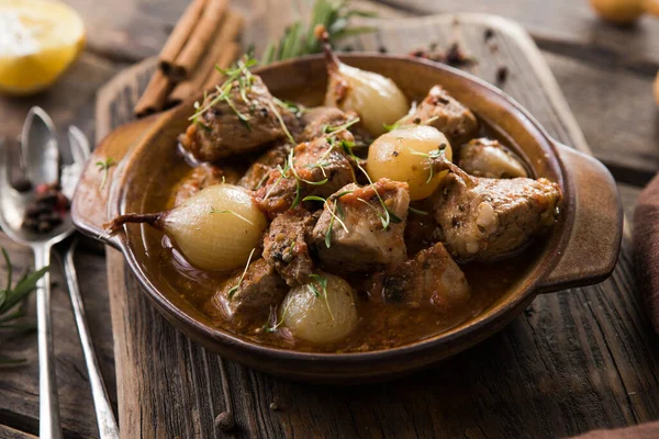 stifado - lezzetli Akdeniz sığır güveci soğan soğanları, tarçın ve baharatlar bir güveçte, siyah ahşap bir masa üzerinde, yukarıdan görüş, yakın çekim