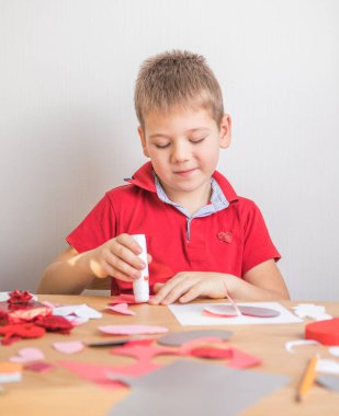 Kırmızı kağıt kalpli DIY tatil kartı, aşkın sembolü. Çocuk Anneler Günü 'nde, Sevgililer Günü' nde, tebrik kartında. Hobi, çocuk sanatı konsepti, kendi ellerinle hediye, çocuklar için fikirler.