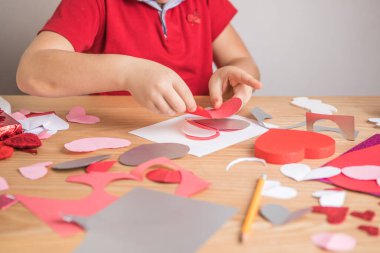 Kırmızı kağıt kalpli DIY tatil kartı, aşkın sembolü. Çocuk Anneler Günü 'nde, Sevgililer Günü' nde, tebrik kartında. Hobi, çocuk sanatı konsepti, kendi ellerinle hediye, çocuklar için fikirler.