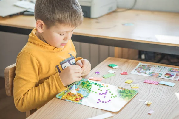 Little boy being creative making homemade do it yourself  dinosaur mosaic. Supporting creativity, learning by doing, learning through experience. Helping child gain access to a creative way of seeing.