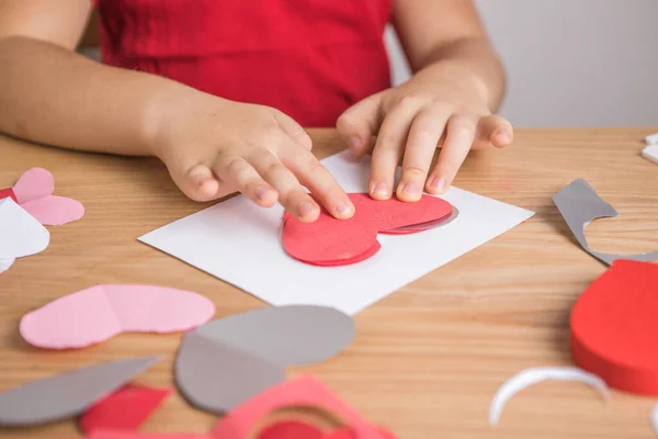 Kırmızı kağıt kalpli DIY tatil kartı, aşkın sembolü. Çocuk Anneler Günü 'nde, Sevgililer Günü' nde, tebrik kartında. Hobi, çocuk sanatı konsepti, kendi ellerinle hediye, çocuklar için fikirler.