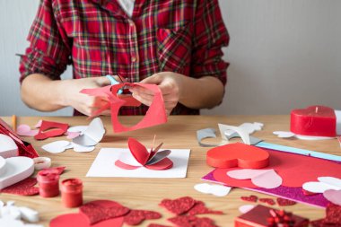 Kırmızı kağıt kalpli DIY tatil kartı, aşkın sembolü. Kız Anneler Günü 'nü, Sevgililer Günü' nü, tebrik kartını hazırlar. Hobi, sanat konsepti, kendi ellerinle hediye.