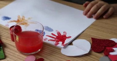 The child draws on a piece of paper with bright colors. 