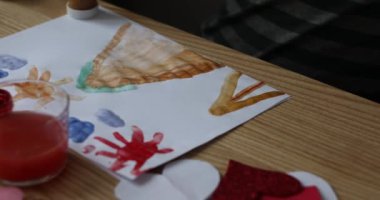 The child draws on a piece of paper with bright colors. 