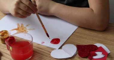 The child draws on a piece of paper with bright colors. 