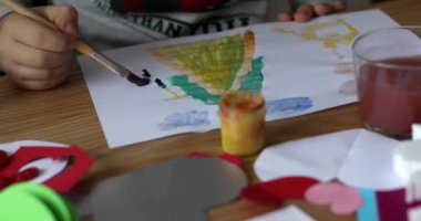 The child draws on a piece of paper with bright colors. 