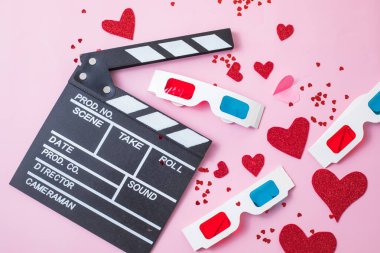 St. Valentine's day Movie night concept. Popcorn, 3d glasses clapper board on pink  background. Cozy holiday plans for lovers