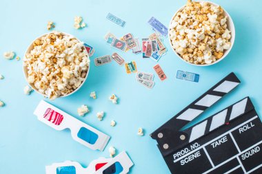 Cinema minimal concept. word movie, popcorn, clapperboard, 3D glasses and tickets top view flat lay on blue background