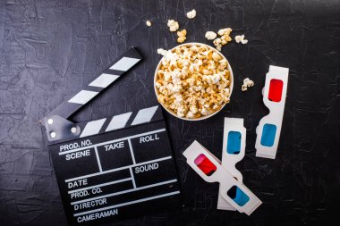 Cinema minimal concept. popcorn, 3d glasses clapper board on black background