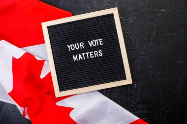 Letterboard sign with the words your vote matters with Canada flag on  black background