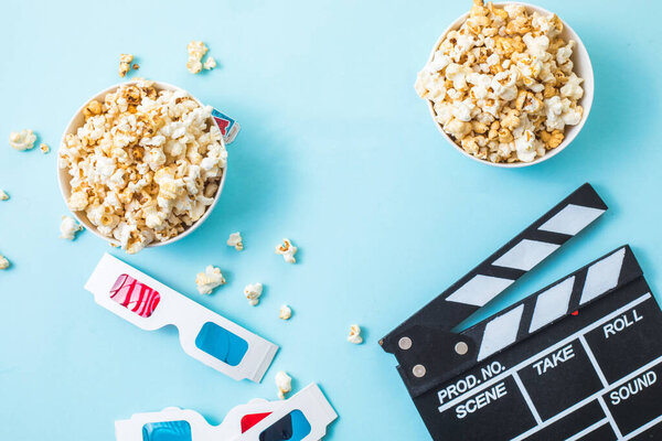 Cinema minimal concept. word movie, popcorn, clapperboard, 3D glasses and tickets top view flat lay on blue background