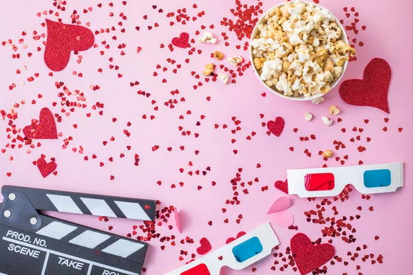 St. Valentine\'s day Movie night concept. Popcorn, 3d glasses clapper board on pink  background. Cozy holiday plans for lovers