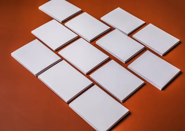 White sheet mockup. Stack of blank name cards. Blank white business card on brown paper background.