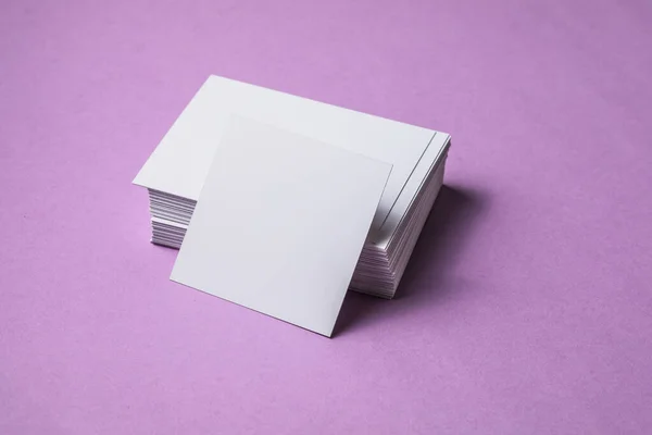 White sheet mockup. Stack of blank name cards. Blank white business card on purple paper background.