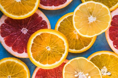 Dilimler, parçalar, bütün olgun sitruslar arka planda. Sulu mandalinalar, portakallar, greyfurtlar, limonlar, limonlar, sarı tuvalde yapraklar var. Meyve suyu hazırlamak için yaz mevsimi egzotik tropikal meyveleri.