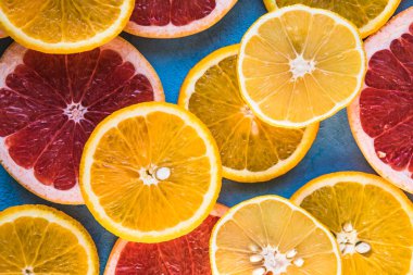 Dilimler, parçalar, bütün olgun sitruslar arka planda. Sulu mandalinalar, portakallar, greyfurtlar, limonlar, limonlar, sarı tuvalde yapraklar var. Meyve suyu hazırlamak için yaz mevsimi egzotik tropikal meyveleri.