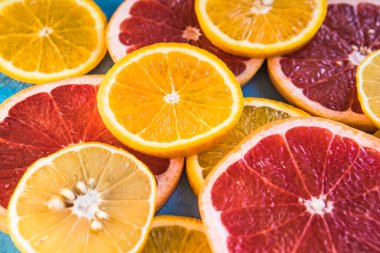 Dilimler, parçalar, bütün olgun sitruslar arka planda. Sulu mandalinalar, portakallar, greyfurtlar, limonlar, limonlar, sarı tuvalde yapraklar var. Meyve suyu hazırlamak için yaz mevsimi egzotik tropikal meyveleri.