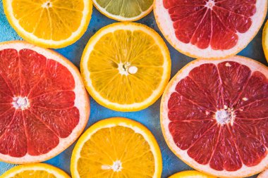 Dilimler, parçalar, bütün olgun sitruslar arka planda. Sulu mandalinalar, portakallar, greyfurtlar, limonlar, limonlar, sarı tuvalde yapraklar var. Meyve suyu hazırlamak için yaz mevsimi egzotik tropikal meyveleri.