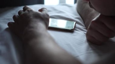 Adam cep telefonu kullanıyor, internette geziniyor ve telefonda mesajlaşıyor.