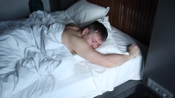 Young man is about to sneeze being ill. Attractive young man sleeping in his bed — Stock Video