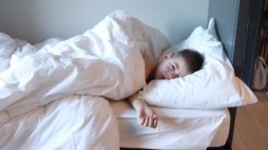Uykucu çocuk yatakta uzanıyor ve ağlıyor. Yatak odasında yorgun bir çocuk..
