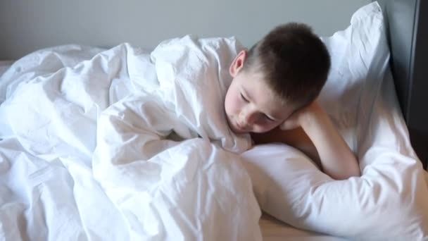 Niño durmiendo, niño soñoliento despertando por la mañana en el dormitorio con luz de la mañana. — Vídeo de stock