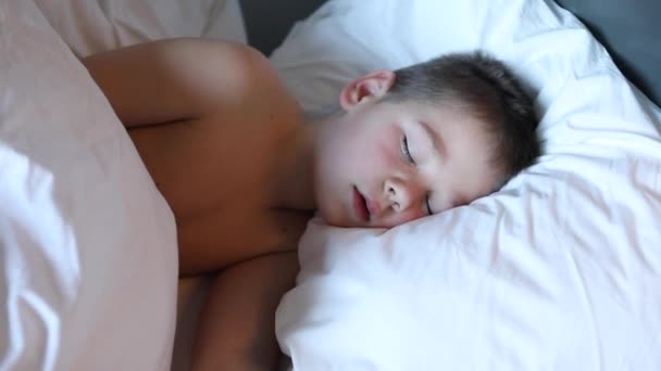 Lindo chico durmiendo en cama con luz de la mañana, precioso niño obtener profundo sueño. — Vídeo de stock