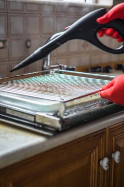 Gloved cleaner washing oven with steamer at home closeup