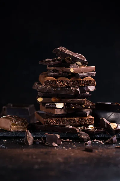 Bar of Chocolate tower pieces. Hazelnut and almond dark chunks of broken chocolate. Sweet food photo concept.